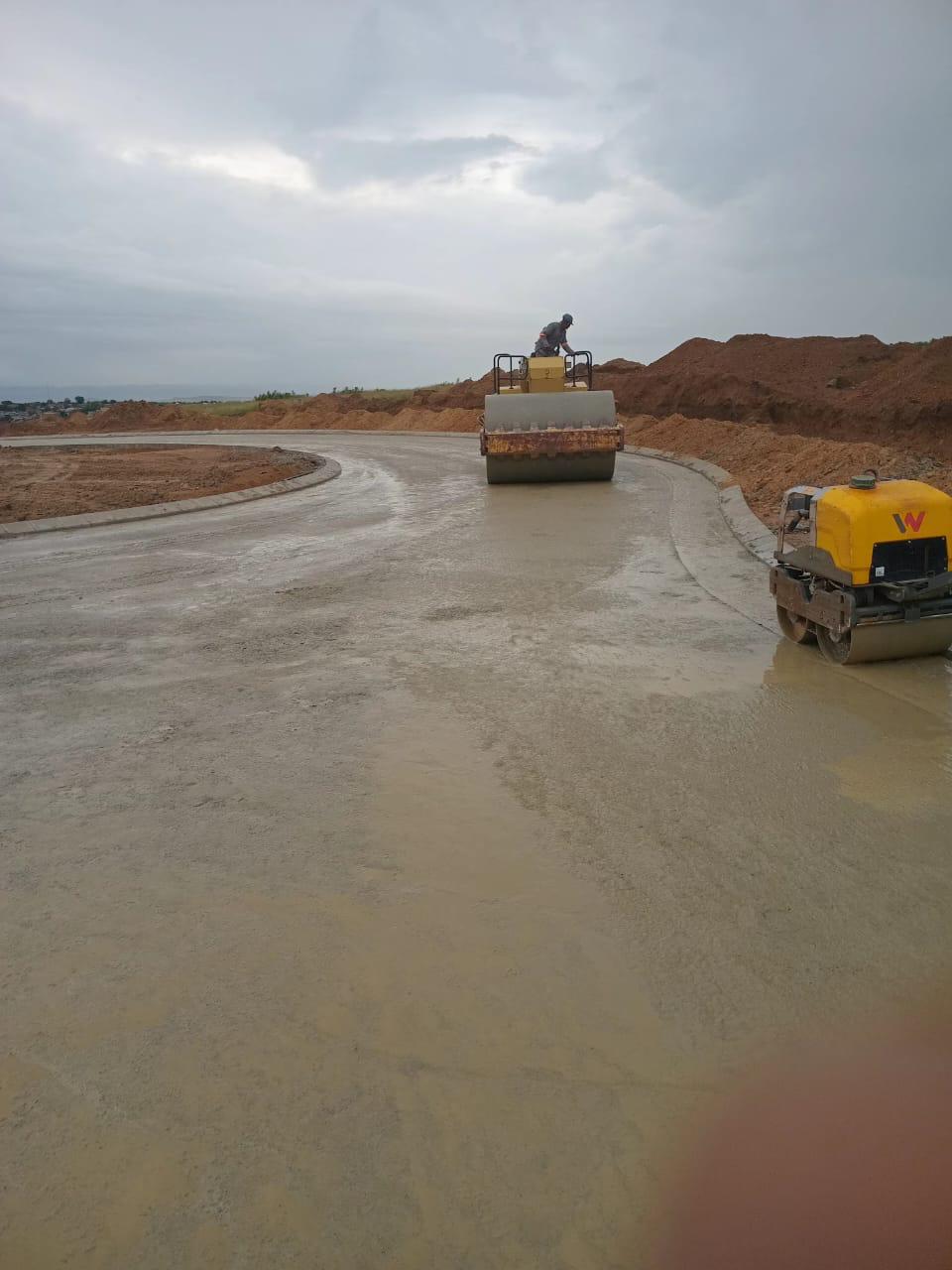 Road roller compacting a wet gravel or soil surface